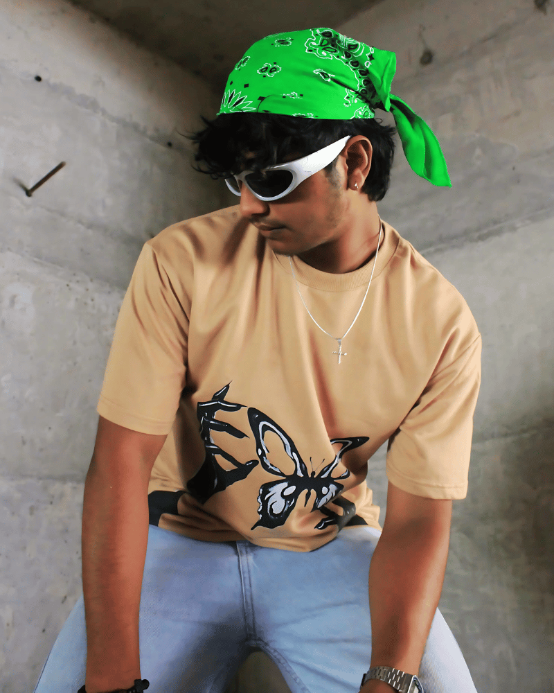 Man wearing Gully Projekt tainted flight graphic t-shirt in beige with butterfly design and green bandana